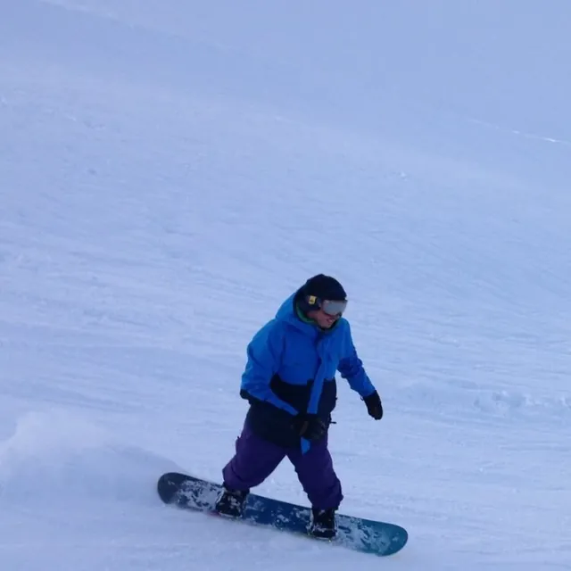 Snowboarding down a snowy slope in a blue jacket