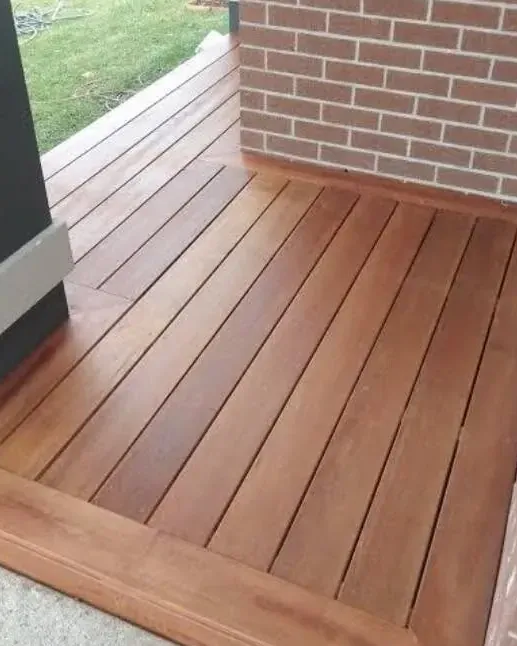 Freshly stained timber deck beside a brick wall