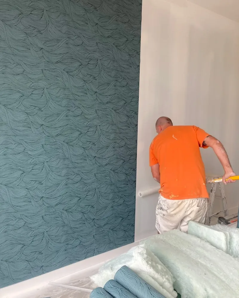 Jef hanging teal wave-patterned wallpaper on a feature wall