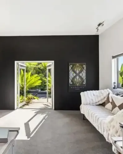 Lounge with a black feature wall and doors open to the garden