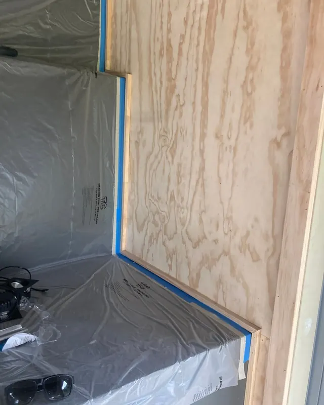 Timber wall trim masked with tape and plastic film, ready for spraying